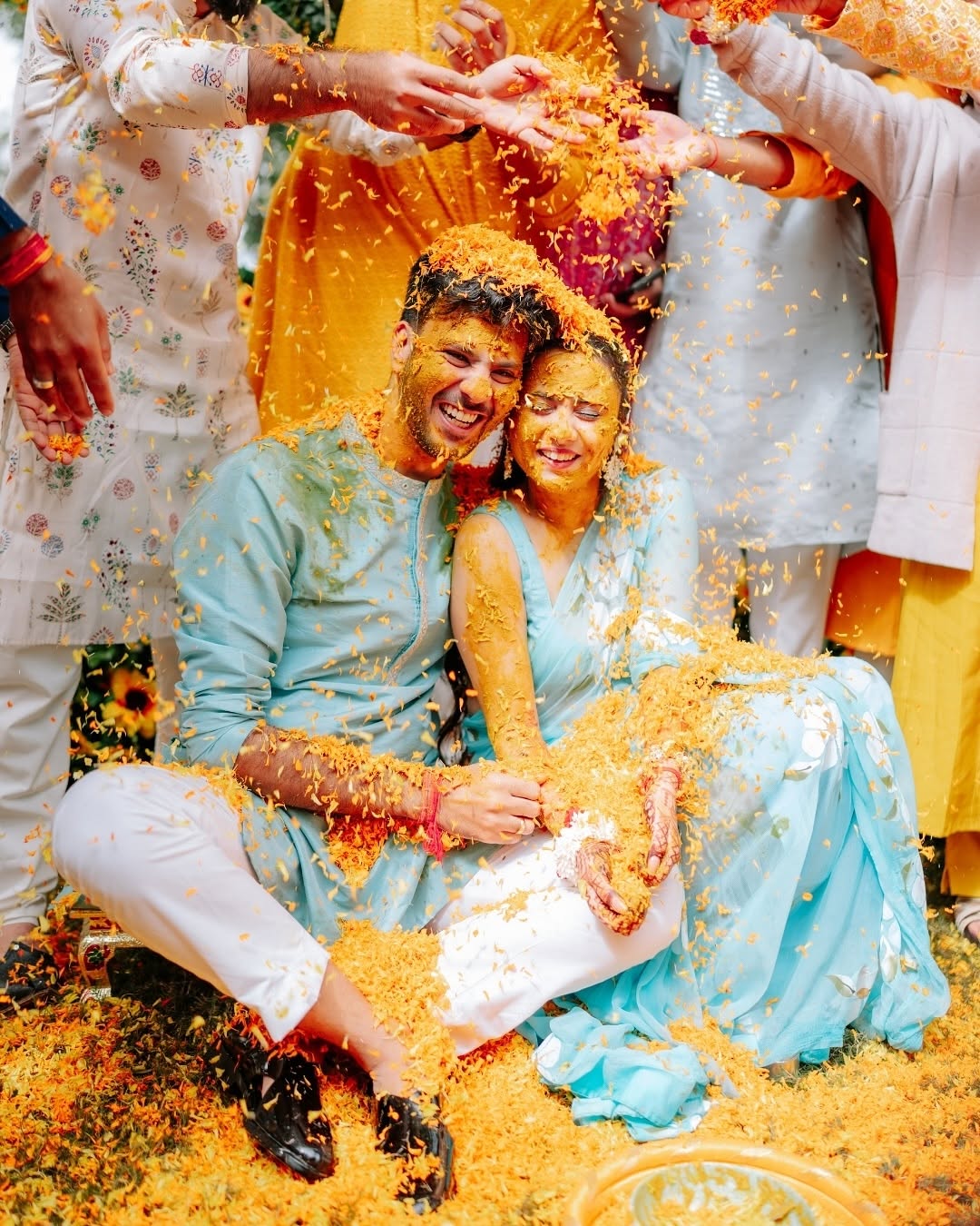 Couple covered in petals during haldi in blue outfits